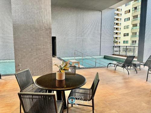 a patio with a table and chairs and a pool at Solaz Smart Living by 123Quarto in Tambaú