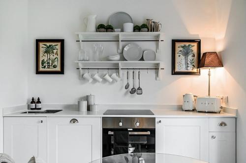 巴斯The Coach House at The Grange的厨房配有白色橱柜和白色台面