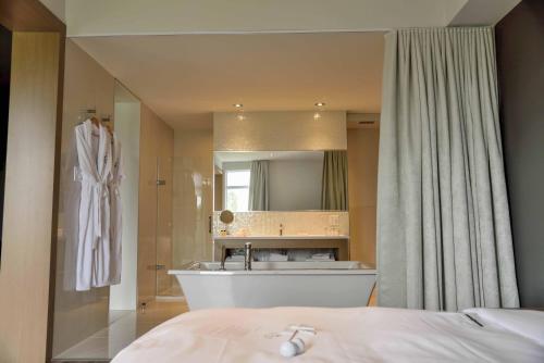 een badkamer met een bad, een wastafel en een spiegel bij La Cache du Golf in Beauceville
