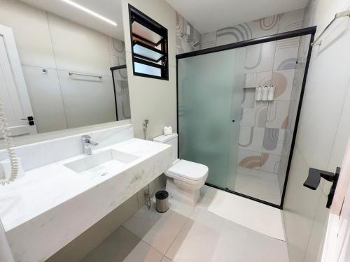 a white bathroom with a sink and a toilet at Pousada Girassol in Bonito