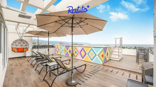 um pátio com cadeiras e um guarda-sol numa varanda em 3B Torre KU 2BR Sofa OceanView Balcony PoolAccess em Puerto Vallarta
