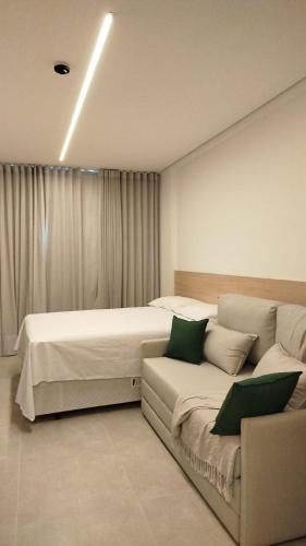 een slaapkamer met 2 bedden en een bank bij Flat Beach Class Verano- Praia de Muro Alto- Porto de Galinhas in Ipojuca