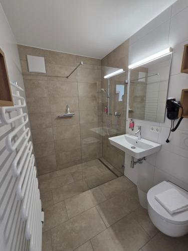 a bathroom with a shower and a toilet and a sink at Naturparkhotel Florence in Weissenbach am Lech