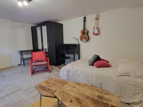 Saint-Cyr-en-ValStudio indépendant tout équipé chez l'habitant的一间卧室，里面有一张床、一张桌子和一架钢琴