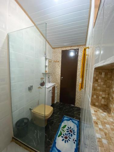 a bathroom with a toilet and a glass door at Recanto da Magia in Palhoça