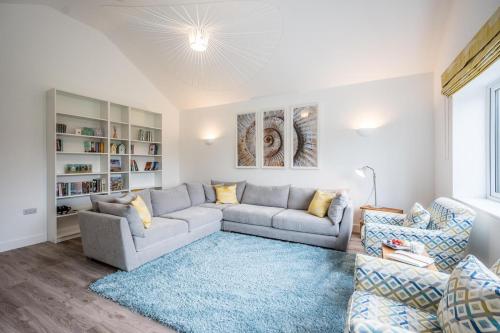 een woonkamer met een grijze bank en een blauw tapijt bij 100 Leiston Road, Aldeburgh in Aldeburgh