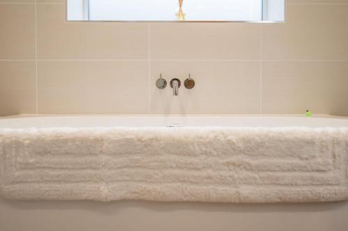 een wit bad met een witte handdoek erop bij 100 Leiston Road, Aldeburgh in Aldeburgh