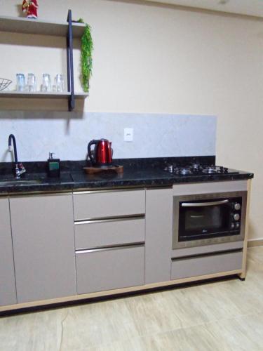 a kitchen with a stove and a microwave at Casa aconchegante e familiar no bairro Vila Nova in Joinville