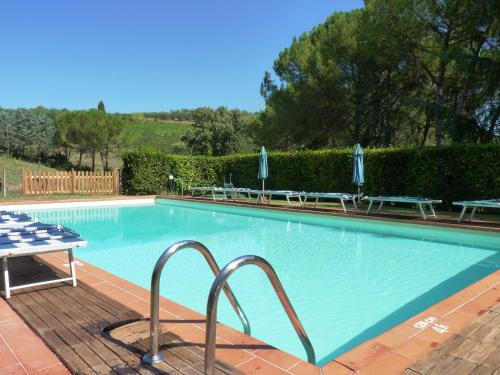 a large swimming pool with a table and umbrellas at Antico Podere Il Bugnolo in Poggibonsi