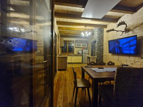 a dining room with a table and a tv on a wall at Chaty Jelenye in Turzovka