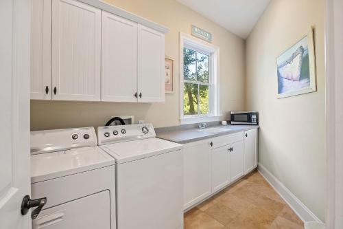 a white laundry room with white cabinets and a window at HH2482: 2482 High Hammock Road in Seabrook Island