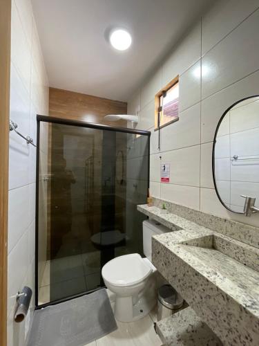 a bathroom with a toilet and a glass shower at Pousada VKG Suites in São Pedro da Aldeia
