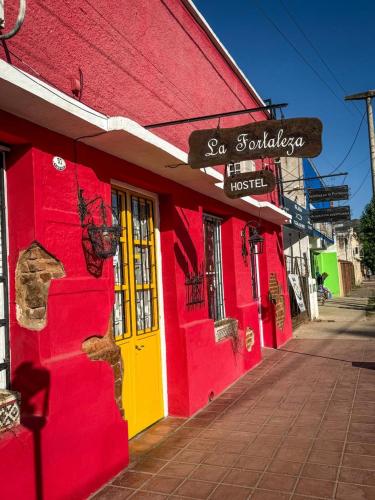 a red building with a yellow door on a street at Hostel La Fortaleza in Bialet Massé