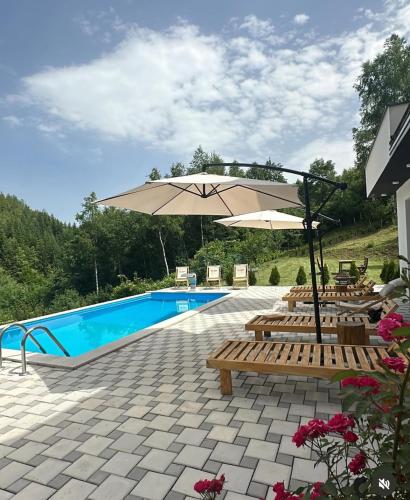 a swimming pool with benches and an umbrella next to a pool at Vila Amore Sarajevo Bjelasnica 