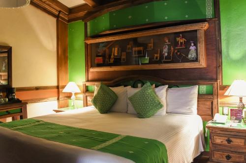 a bedroom with a large bed with green walls at Nuestras Raíces Hotel - Museo - Restaurante in San Cristóbal de Las Casas