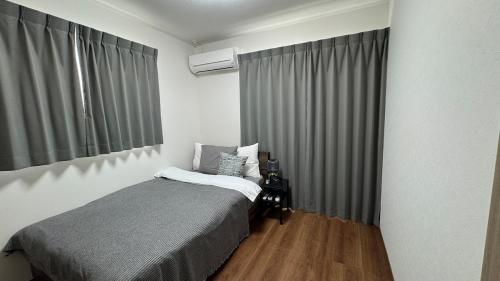 Un dormitorio pequeño con una cama y una ventana. en 大津町国際交流会館, en Ozu