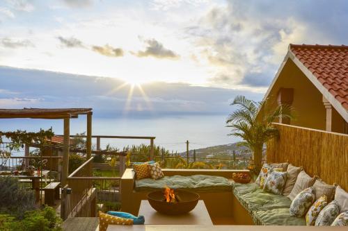 a patio with a couch and a table and the sun at Yeotown Madeira Wellness Hotel and Nature Stay in Arco da Calheta