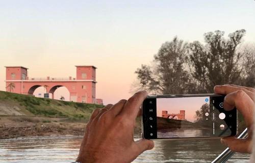 a person taking a picture of a river with a cell phone at MorenoPLAZA in Concepción del Uruguay