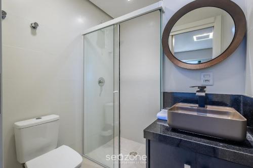 a bathroom with a sink and a toilet and a mirror at Sua estadia completa a poucos minutos do mar em BC – STLs in Balneário Camboriú