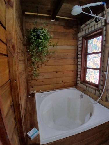 Una bañera en un baño de madera con ventana. en Atelier House, en Florianópolis