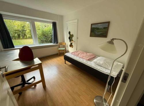 a bedroom with a bed and a desk and a window at The Coziest Farm Holiday In The Countryside in Tommerup