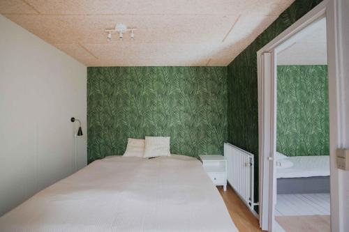 a bedroom with a white bed and green wallpaper at Stay In Hindemaes Historic Managers House in Ullerslev