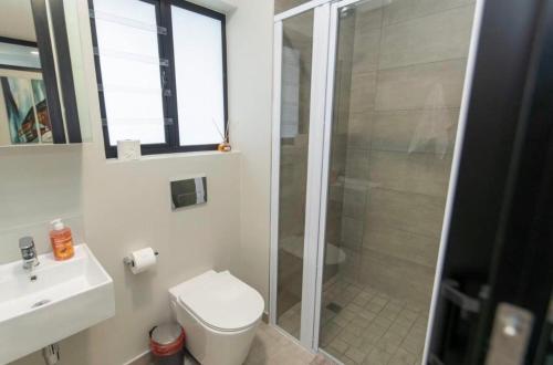 a bathroom with a shower and a toilet and a sink at Beachfront Getaway in Gqeberha