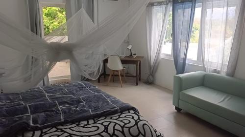a bedroom with a bed and a chair and a desk at Les zoliviers in Petite Rivière