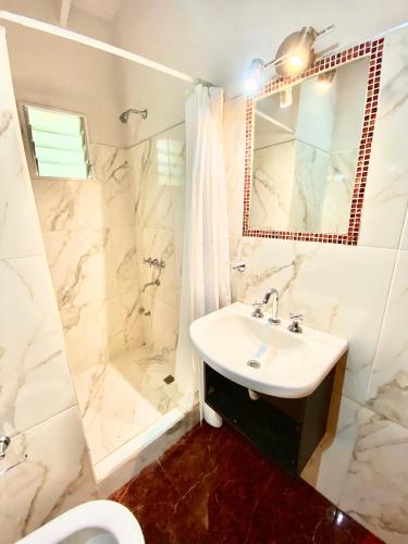 a white bathroom with a sink and a shower at La Ribera Aparts in Santa Rosa de Calamuchita