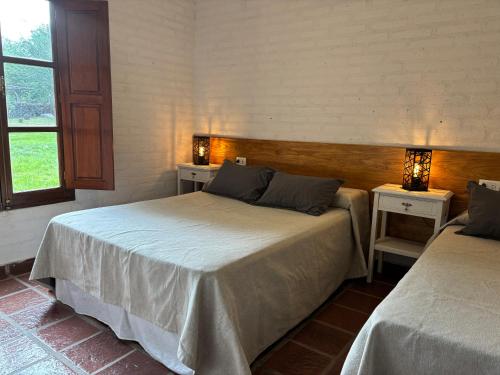 a bedroom with two beds and two tables with lamps at La Ribera Aparts in Santa Rosa de Calamuchita
