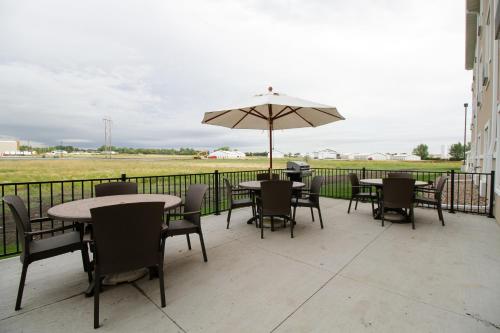 a patio with tables and chairs and an umbrella at Cobblestone Hotel & Suites - Devils Lake in Devils Lake