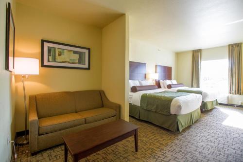 a hotel room with two beds and a couch at Cobblestone Hotel & Suites - Devils Lake in Devils Lake