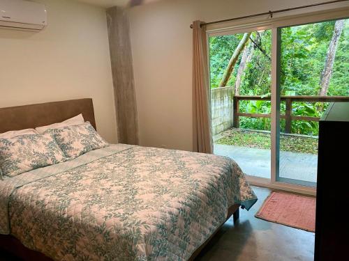 a bedroom with a bed and a large window at Tropical Jungle House in Coxen Hole