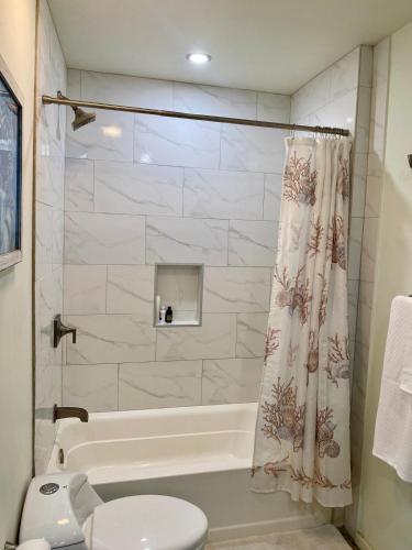 a bathroom with a tub and a toilet and a shower at Tropical Jungle House in Coxen Hole