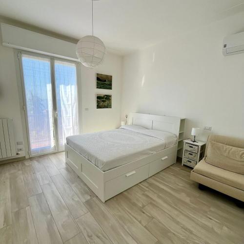 a white bedroom with a bed and a couch at La vista Azzurra in Bordighera
