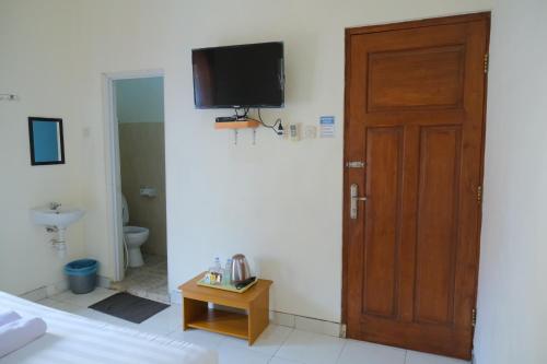 Habitación con puerta y TV en la pared en New Amandani House by Yurooms, en Kejayan