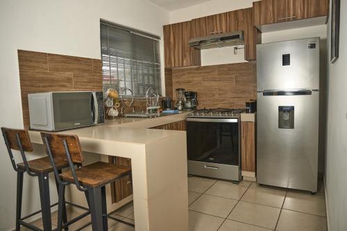 a kitchen with a refrigerator and a counter with chairs at Casa almendros 31 in Ciudad Guzmán