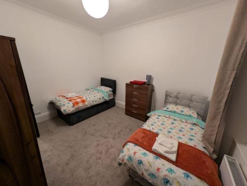 a bedroom with two beds and a dresser at Blackthorn Manor in Greenock