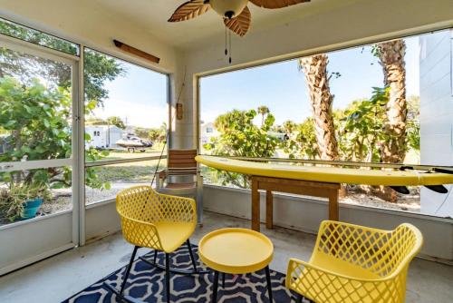 a room with a surfboard on a table and chairs at Boho Cocoa Beach 1BR Steps to Beach in Cape Canaveral