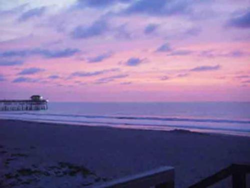 a view of the beach with a pier in the distance at 1BR Cocoa Beach Home - 1 Min to Beach in Cape Canaveral