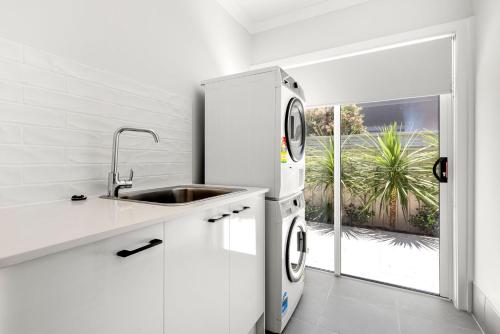 una cucina bianca con lavello e frigorifero di Pearl Jervis Bay - Luxury with Swimming Pool a Callala Beach