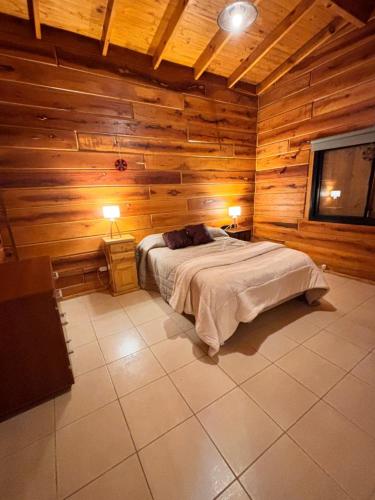 Cabaña Alpina con Terraza Panorámica في لا كومبريسيتا: غرفة نوم بها سرير في جدار خشبي