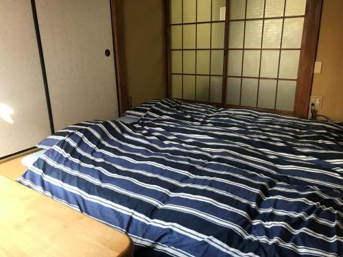 a blue and white striped bed in a room at YabFarm Lodge 102 in Kashiwa
