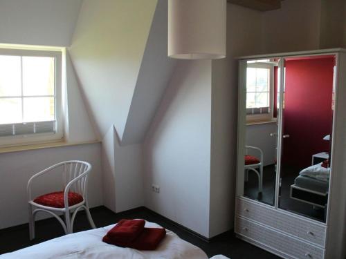 una camera da letto con un letto, una sedia e uno specchio di Holiday apartment with 2 bedrooms a Hof Dranske