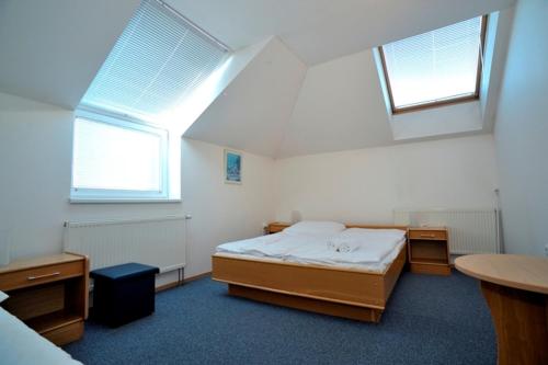 a bedroom with a bed and two windows at Penzion Šenk Pardubice in Pardubice