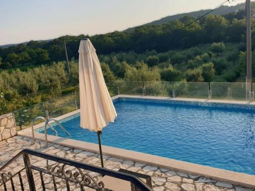 a white umbrella sitting next to a swimming pool at Holiday home with 3 bedrooms in Ripenda Kras