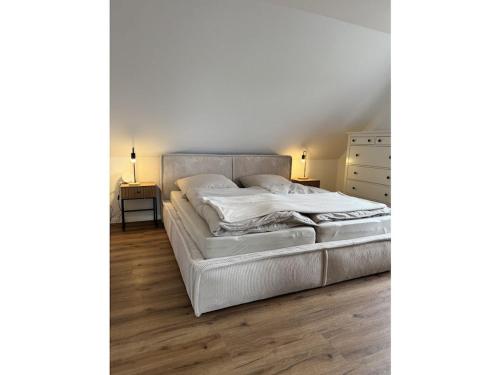 1 cama blanca en un dormitorio con suelo de madera en Michael's Elbe Dream, en Krautsand