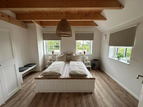 a bedroom with a large white bed with two windows at The Linnebargs, House 1 in Bisdorf
