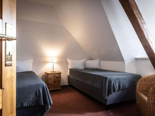 Holiday apartment Gutshof Bastorf في Bastorf: غرفة نوم بها سريرين وطاولة مع مصباح