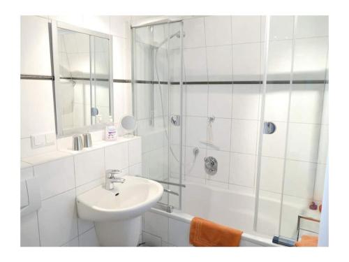 a white bathroom with a sink and a shower at 4-star holiday apartments Weber in Winningen